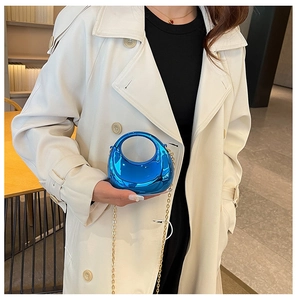 Chic metallic blue mini bag with gold chain strap styled on a white trench coat