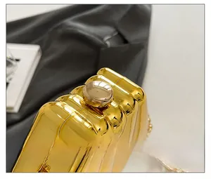 Detail showing the golden wave-textured metal surface and ball clasp of the evening clutch