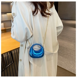 Close-up of metallic electric blue mini handbag with gold chain strap on white coat