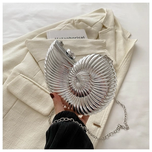 Détail d'une pochette argentée en forme de coquillage avec finition miroir et chaîne métal