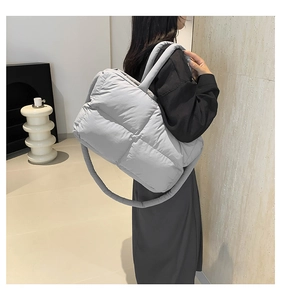 Détail d'un sac cabas matelassé gris clair avec poignée rembourrée et surpiqûres