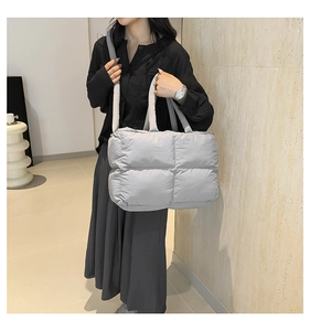 Close-up of light grey quilted nylon tote bag with wide handles and padded texture