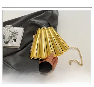Detail of gold shell evening bag with pleated metallic finish and chain strap