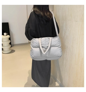 Detailed back view of a light grey quilted puffy tote bag on a model shoulder