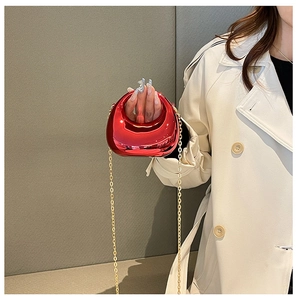 Close-up of vibrant red metallic mini evening bag with elegant gold chain and cutout handle