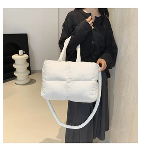 Detail of white quilted nylon handbag showing the puffy texture and soft shoulder strap