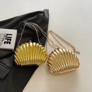 Elegant gold shell evening clutch with metal chain strap on minimalist backdrop