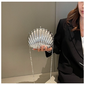 Detail of silver shell-shaped evening bag with metallic texture and chain strap