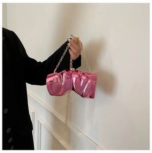 Macro shot of bright pink metallic evening clutch with gold chain and irregular shape