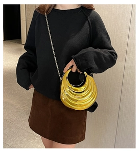 Detail of gold crescent evening bag with metallic wave texture and chain strap