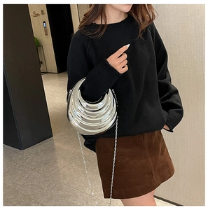 Silver crescent evening bag with tiered ripples and metallic chain strap worn by model