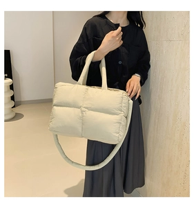 Detail of cream quilted puffer tote bag with durable handles and long strap