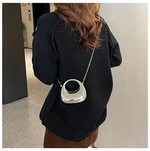 Silver crescent mini evening bag with mirror finish and metallic chain strap on model