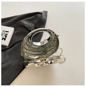 Macro detail of silver liquid metal evening bag showing wavy texture and round handle
