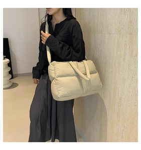 Quilted cloud shoulder bag in beige nylon fabric shown on model in minimalist setting