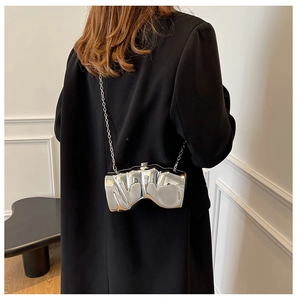 Detailed view of silver metallic fluid-style evening bag with slim chain strap on model
