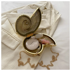 Vue détaillée de l'intérieur du sac de soirée coquillage doré avec cosmétiques