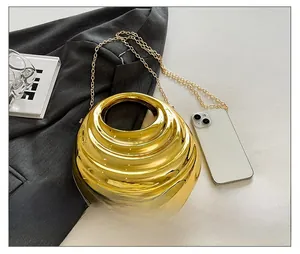 Macro view of gold spherical evening bag with metal ring handle and crossbody chain
