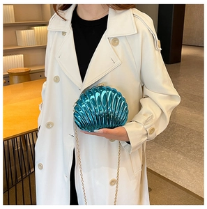 Close-up of metallic blue shell clutch bag with gold chain and radial texture