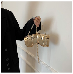 Detail of artistic gold wing-shaped box clutch with molten metal texture and chain