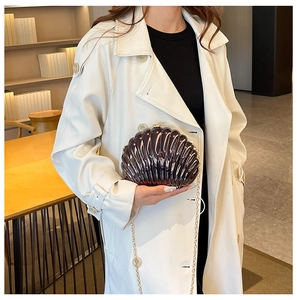 Close-up of a shell-shaped evening clutch bag with golden chain and glossy finish