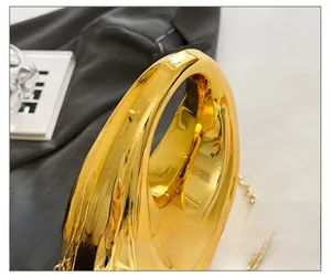 Detailed macro of golden handle on shiny evening bag with metallic chain and glossy finish