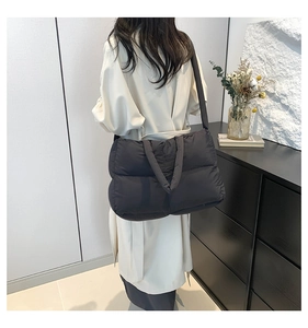 Detailed view of black quilted puffer tote bag on shoulder with plush texture and padding