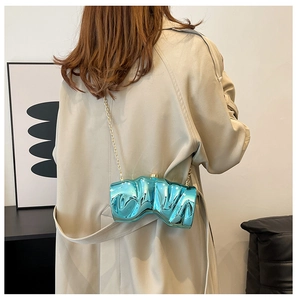 Detail of blue electroplated evening bag with wavy texture and gold chain strap