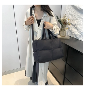 Detail of black quilted puffer tote bag showing waterproof nylon texture and wide strap