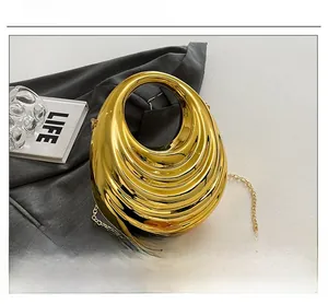 Detail shot of golden oval evening clutch featuring a streamlined layered texture and chain
