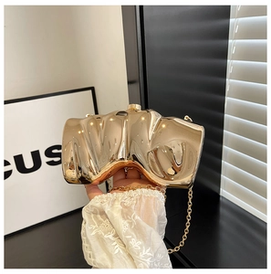 Close-up of golden wavy box clutch with metallic finish and chain strap held by lace sleeve