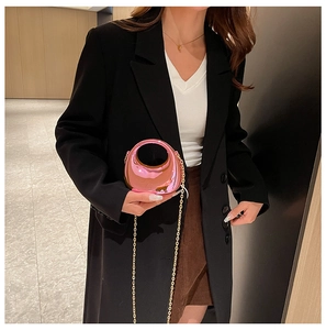 Close-up of mini pink mirror acrylic crescent bag with golden chain held by a model