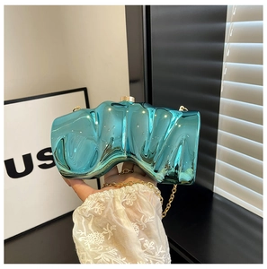 Macro view of cyan blue wing-shaped clutch bag with polished metallic finish and chain