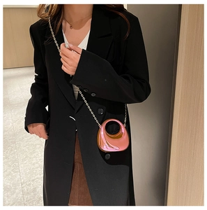 Mini pink metallic half-moon bag with gold chain and round cutout handle shown on model