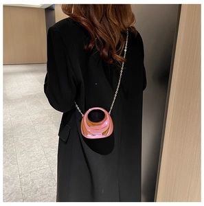 Close-up of mini metallic pink round handle bag with gold chain strap on a black blazer