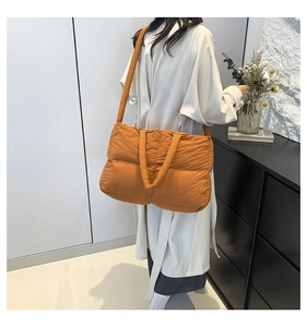 Quilted orange tote bag shown in use, featuring puffy down-style texture and large capacity