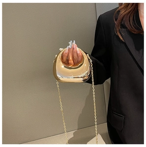 Macro view of gold metal evening bag with circular hollow handle and crossbody chain strap