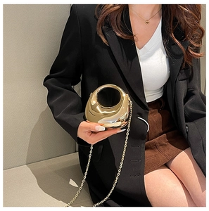 Mini gold crescent bag with sleek cutout handle and chain strap on a black blazer