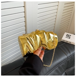 Close-up of golden metallic clutch bag featuring a unique pleated texture and chain strap