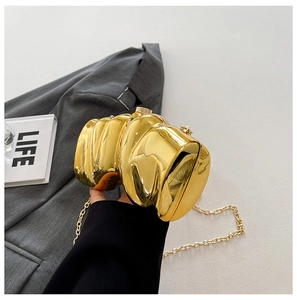 Golden pleated mirror clutch bag with chain strap shown in a chic lifestyle setting
