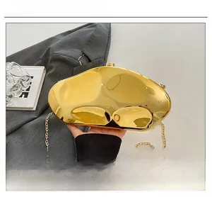 Dettaglio della borsa a mano specchiata dorata con catena su sfondo moda grigio chic