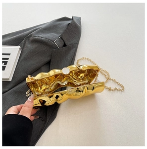 Macro view of metallic gold clutch bag featuring unique wave-like texture and golden chain