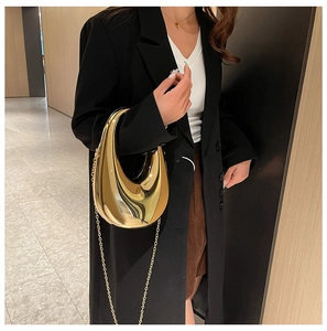 Detailansicht einer goldfarbenen Sichel-Handtasche mit eleganter Kette am Blazer-Outfit
