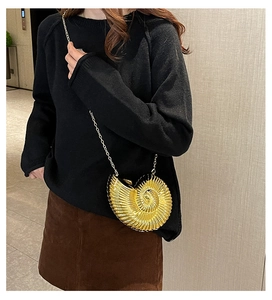 Schicke goldene Muschel-Abendtasche aus Metall mit Kettenriemen am Modell gezeigt