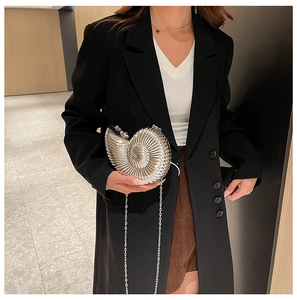 Makroaufnahme einer silbernen Muschel-Clutch mit metallischer Spiralstruktur und Kette
