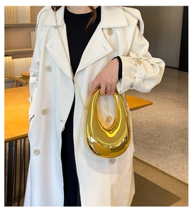 Nahaufnahme einer goldenen Metallic-Abendtasche in Halbmondform mit schicker Kette
