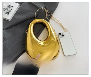 Goldene Clutch in Tropfenform mit Kette im Größenvergleich zum Smartphone gezeigt