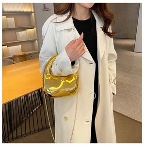 Chic gold mirrored pebble-shaped clutch bag with delicate chain strap shown on model