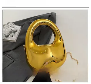 Detailed top view of gold metallic evening clutch bag with ring handle and chain strap