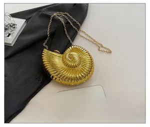 Detailansicht der goldenen Muschel-Abendtasche mit Metallstruktur und Kettenriemen